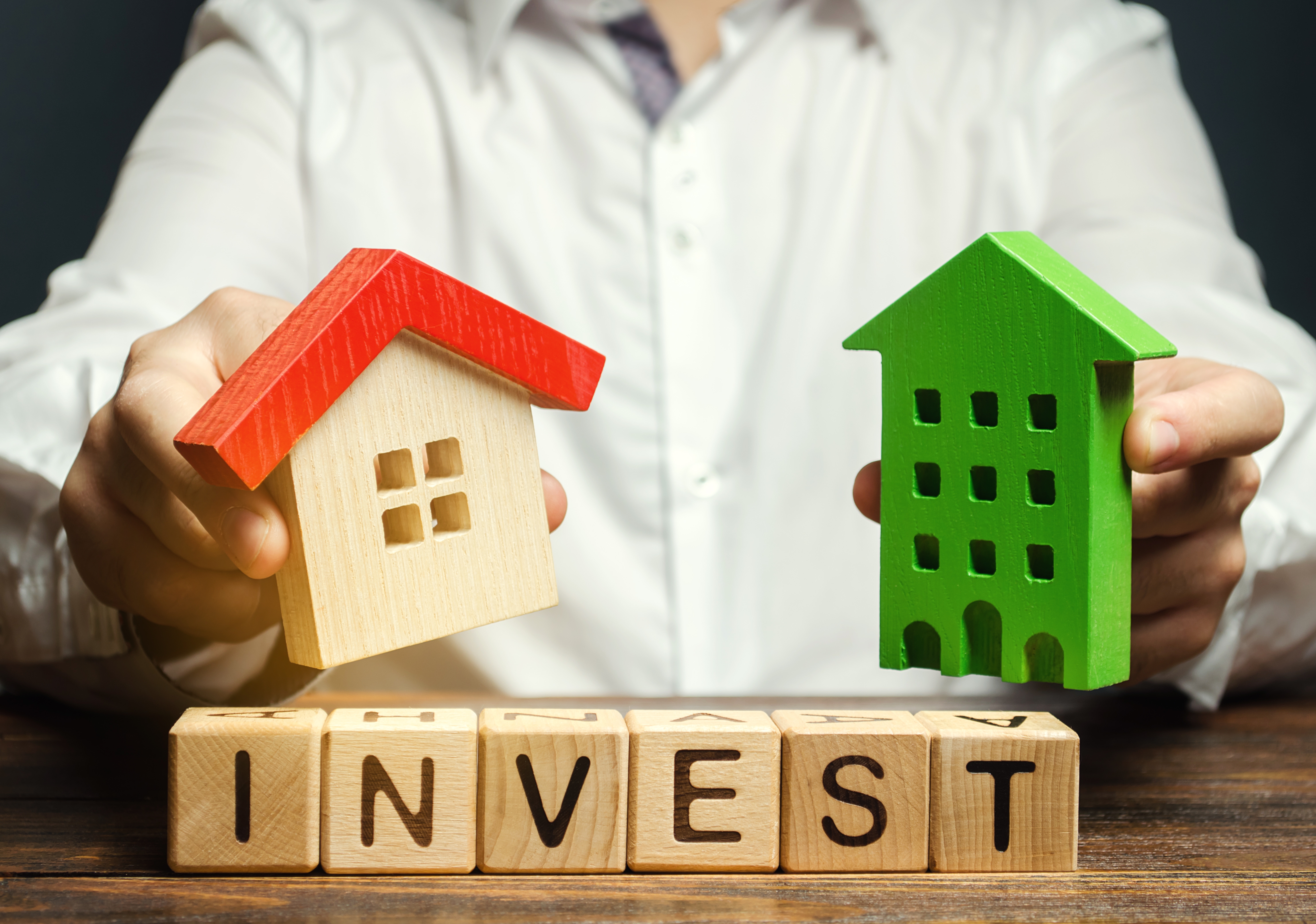 Documents with financial charts, calculator, and pen comparing property and shares for investing in property vs shares analysis.